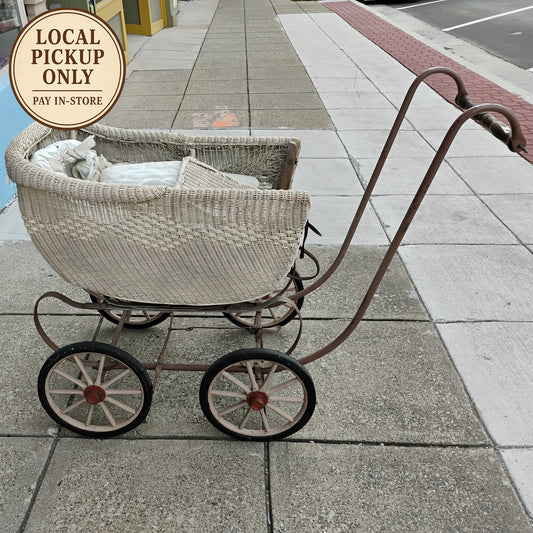 Vintage-style wicker baby buggy on a sidewalk with 'Local Pickup Only' sign.