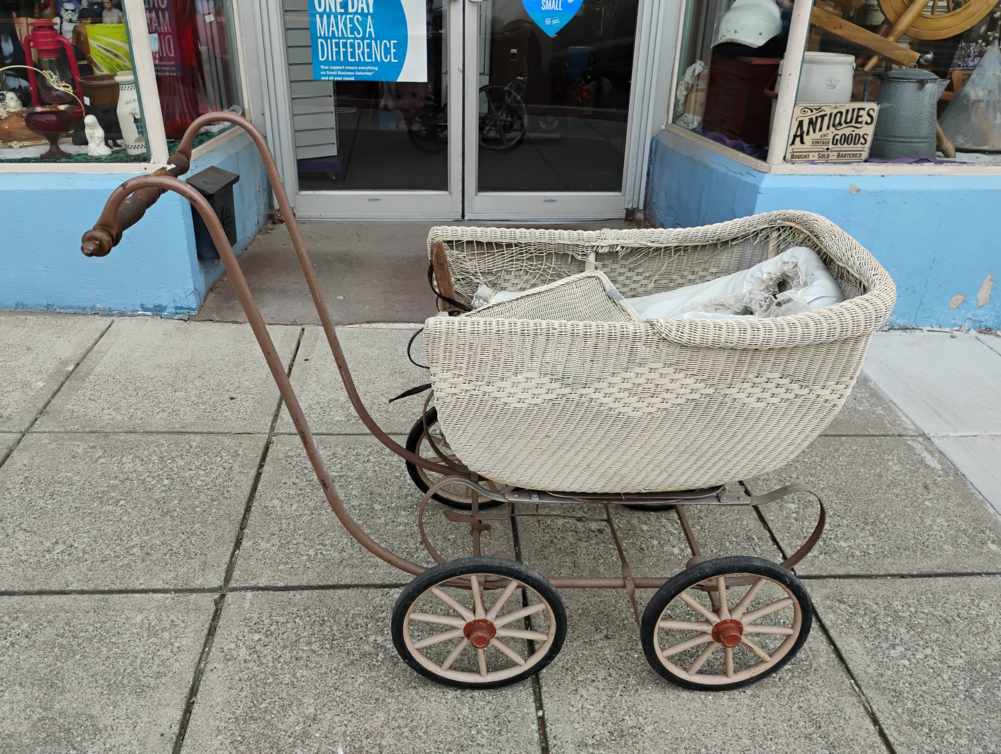 Vintage-style baby buggy with wicker basket on a sidewalk